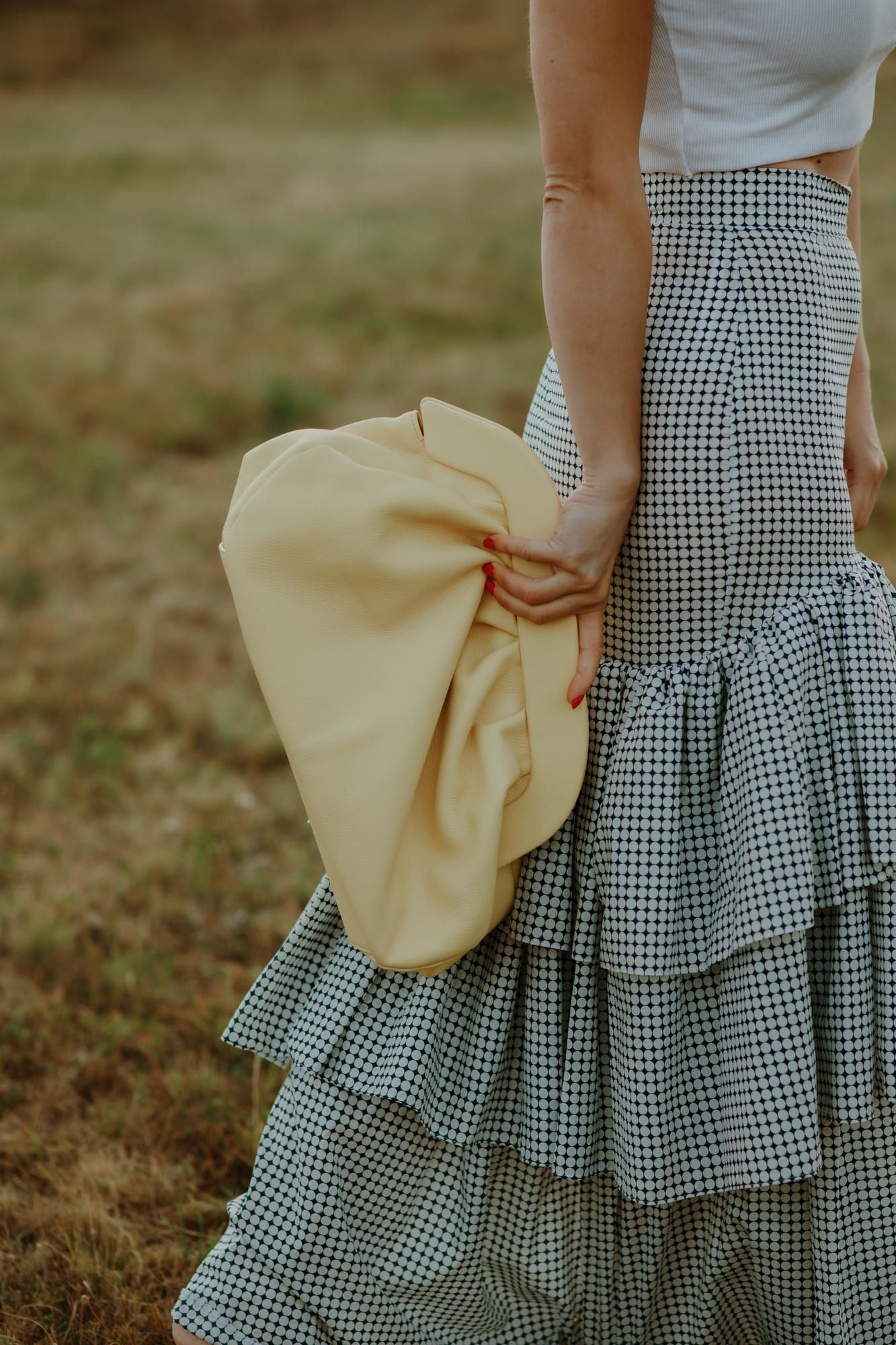 Žuta PELEZZE pouch tašna nošena uz gingham suknju u polju